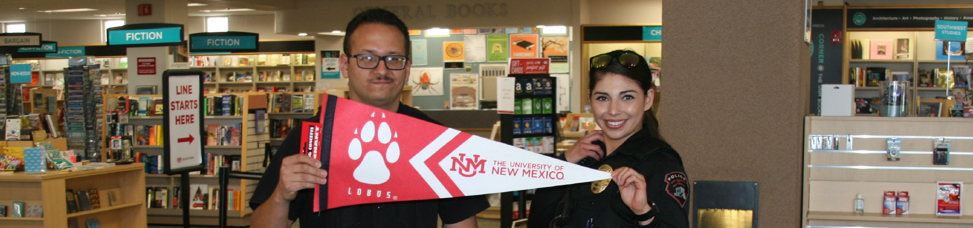 Officers pose with Go Lobos banner inside bookstore