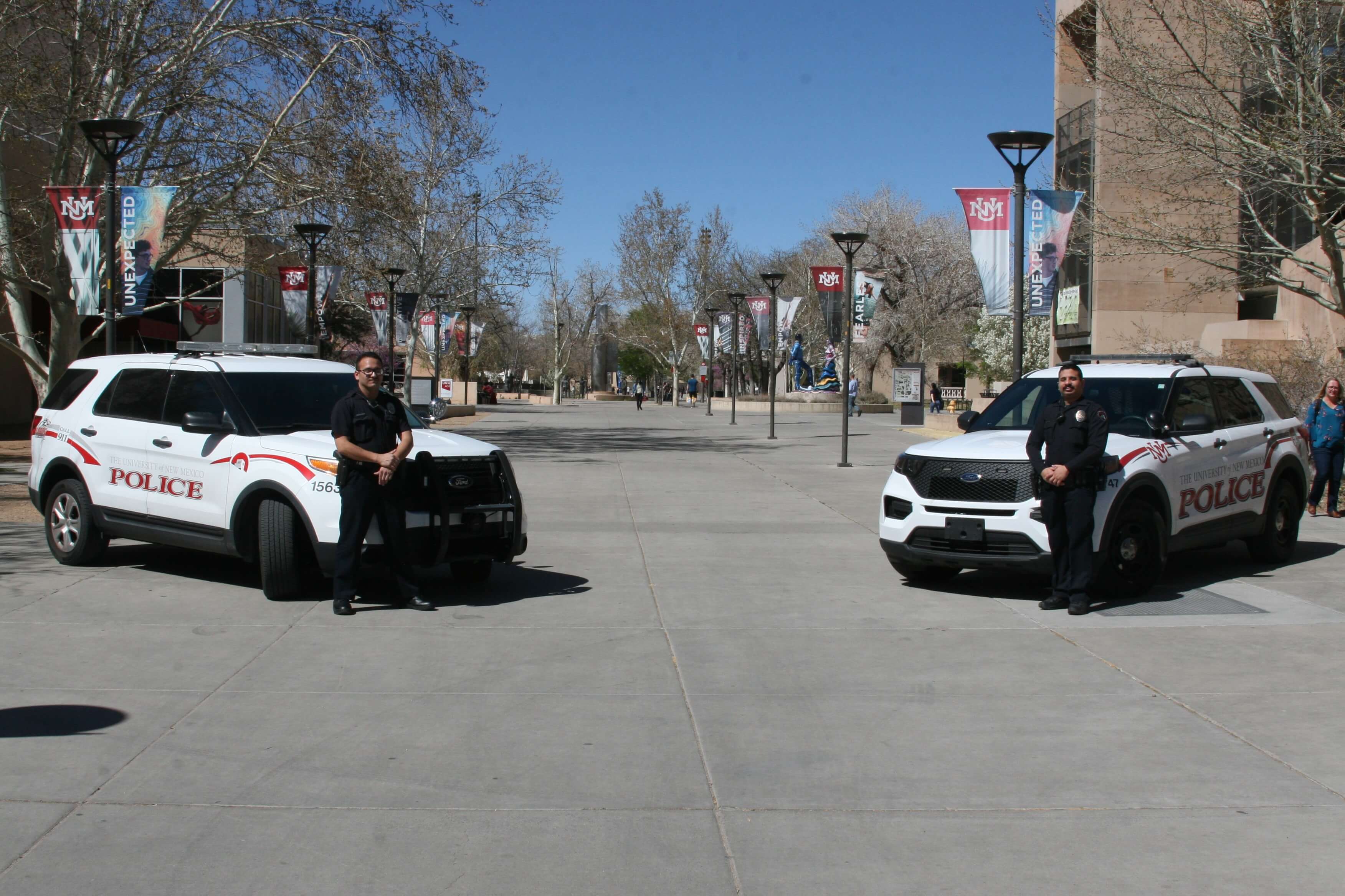 two UNM PD pose with their vehicles at Cornel Mall on UNM Campus